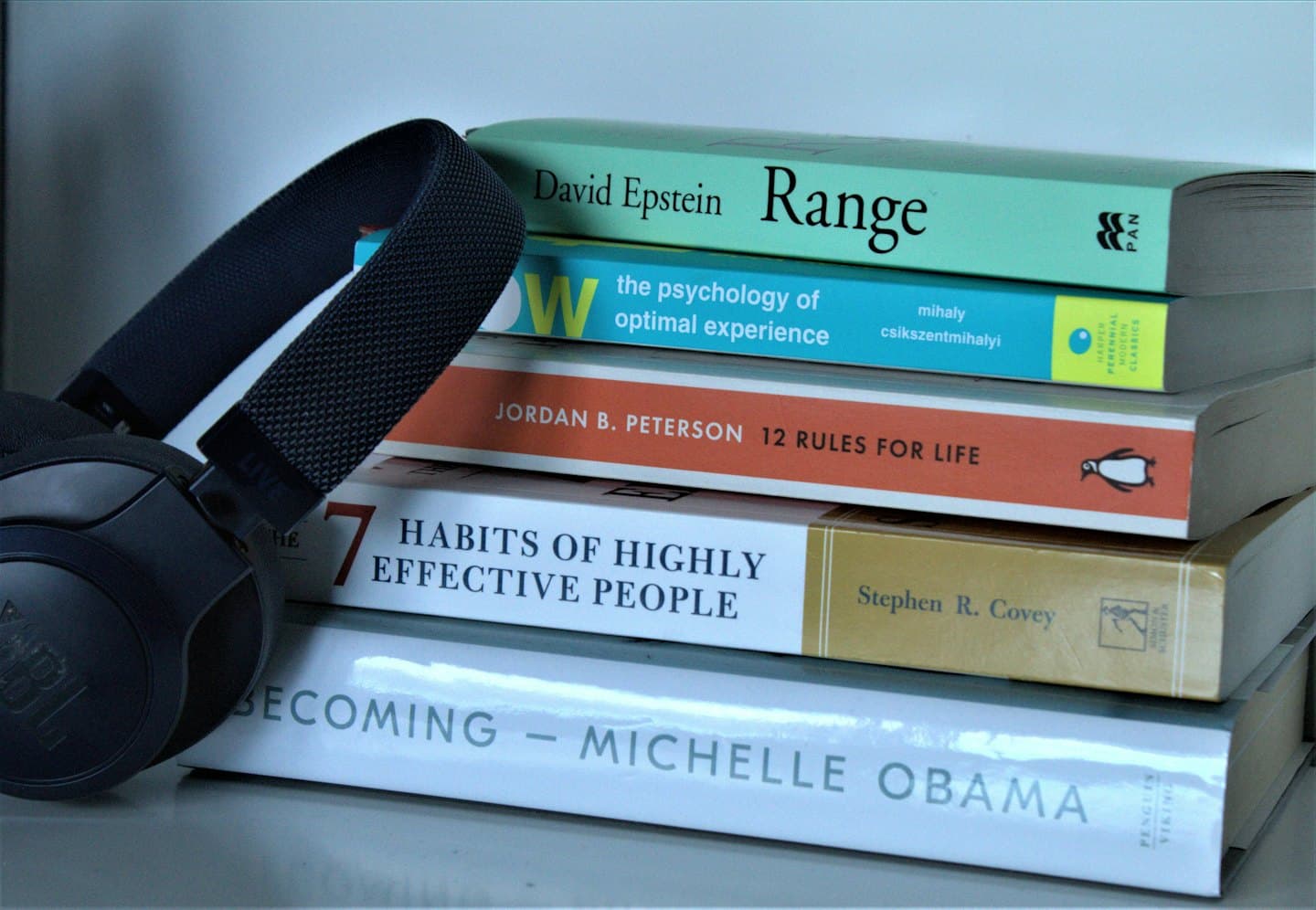 Stack of self-help books with headphones on top.