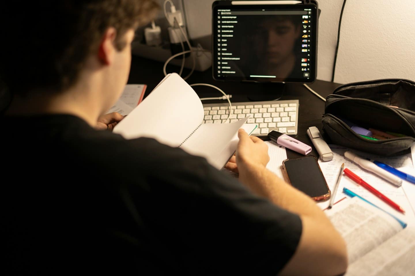 Person studying at a desk with notebook and supplies.